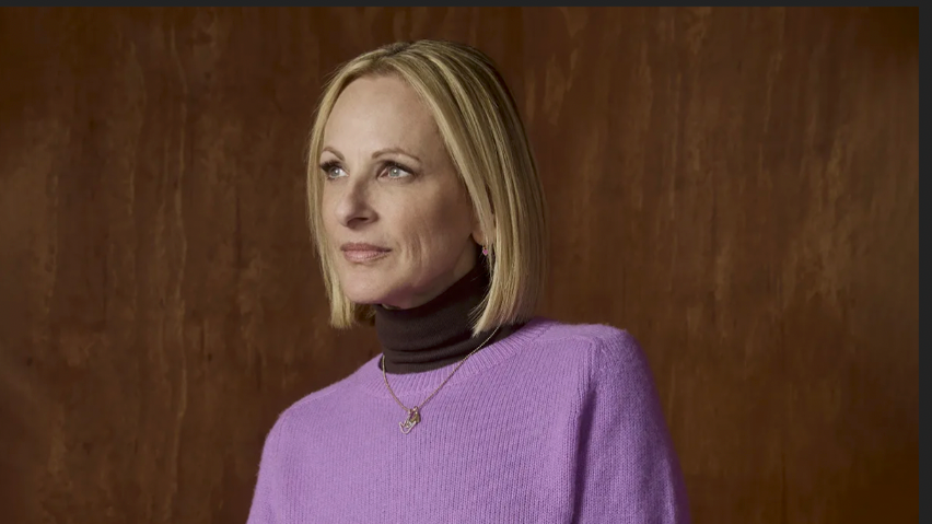woman with shoulder-length blond hair wearing a light purple sweater